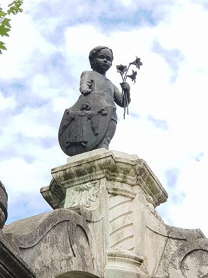 Ein Buberl mit Blumen und Kindl: Diese Figur steht auf dem wunderschönen Reiherbrunnen am Regerplatz in der Oberen Au.