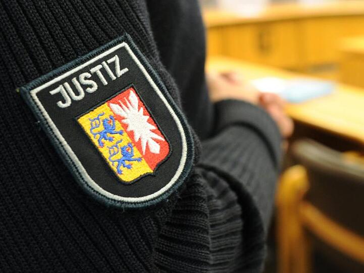 Ein Justizbeamter steht im Sitzungssaal. Foto: Angelika Warmuth/dpa/Archivbild