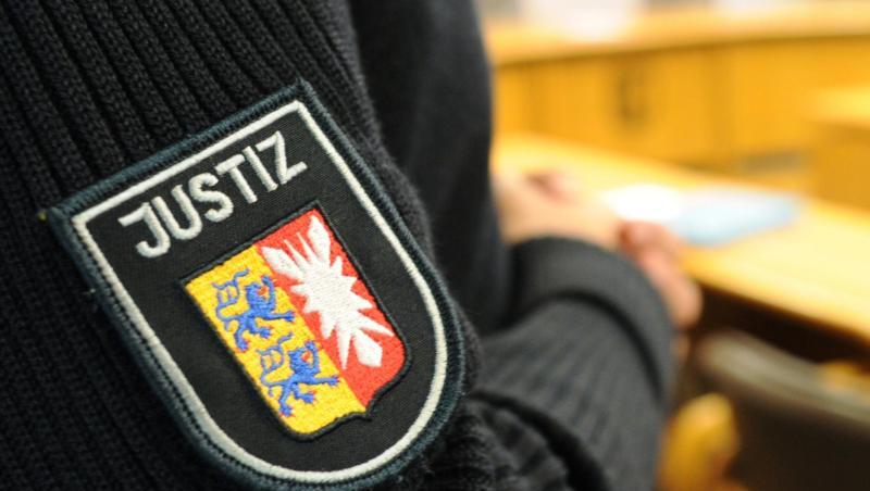 Ein Justizbeamter steht im Sitzungssaal. Foto: Angelika Warmuth/dpa/Archivbild