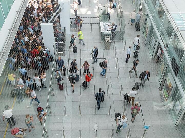 Fluggäste betreten den Sicherheitscheck-Bereich des Terminal 2 im Münchner Flughafen. Foto: Peter Kneffel