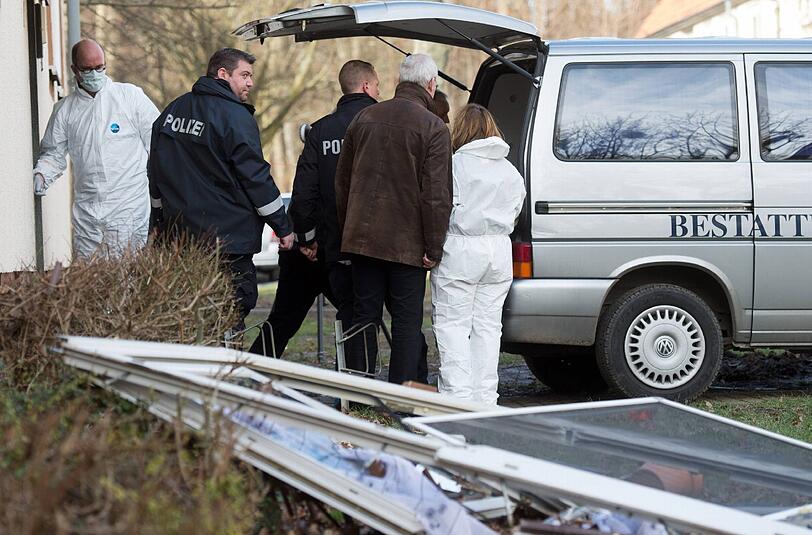 Spurensicherungs-Experten und andere Polizisten stehen vor dem Unglückshaus in Salzgitter - ebenso wie der Wagen, mit dem die drei Leichen abtransportiert werden.