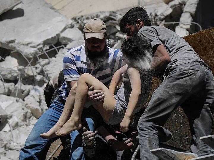 Mitglieder der syrischen Weißhelme und Freiwillige retten ein verletztes Kind aus den Trümmern eines Gebäudes, das bei einem Luftangriff durch die syrischen Regierungskräfte beschädigt wurde.