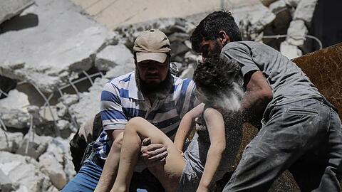 Mitglieder der syrischen Weißhelme und Freiwillige retten ein verletztes Kind aus den Trümmern eines Gebäudes, das bei einem Luftangriff durch die syrischen Regierungskräfte beschädigt wurde.