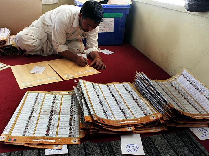 Auf dem Boden knieend zählt ein Wahlhelfer in Kabul Stimmen aus.