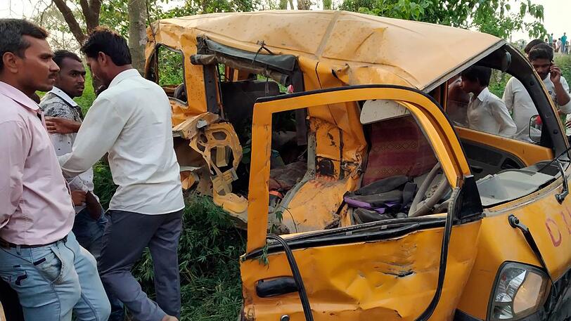 Inder stehen an einer Unfallstelle, an der ein Schulbus von einem Zug erfasst wurde. Bei der Kollision eines Zuges mit einem Schulbus sind in Indien mindestens 13 Kinder ums Leben gekommen.