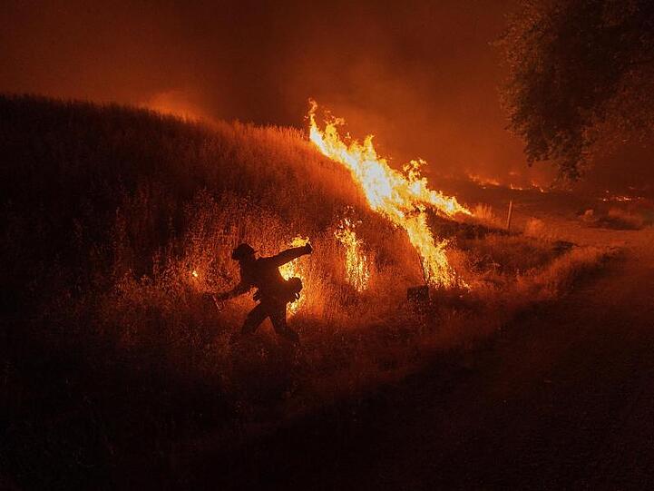 Ein Feuerwehrmann entzündet kontrollierte Gegenfeuer, um die Ausbreitung des Waldbrands zu verhindern.