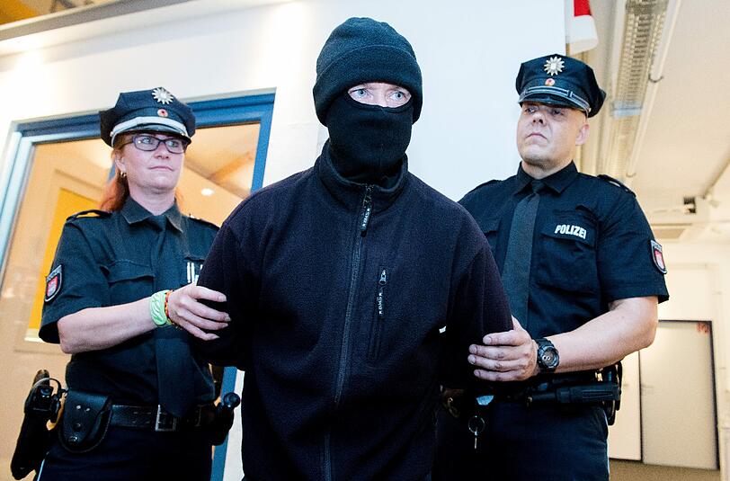 Polizisten nehmen einen als Einbrecher verkleideten Mann fest (gestellte Szene). Foto: Daniel Bockwoldt/Illustration