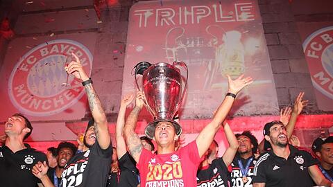 Thiago (M) und seine Teamkollegen feiern mit dem Pokal. Foto: Marco Donato/FC Bayern München AG/dpa