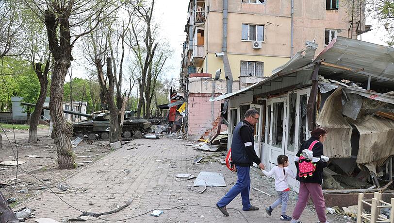 Menschen laufen durch das zerstörte Mariupol.