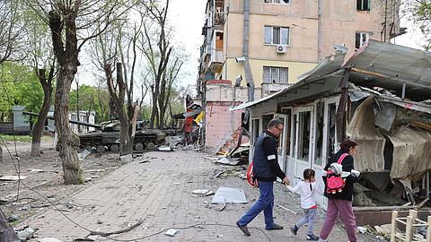 Menschen laufen durch das zerstörte Mariupol.