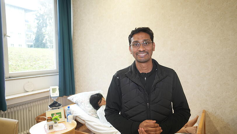 Fortzubildender Mohamed Rafi Esmael. Der geb&uuml;rtige Inder steht vor einer der lebensnahen und menschenschweren Pflegepuppen.
