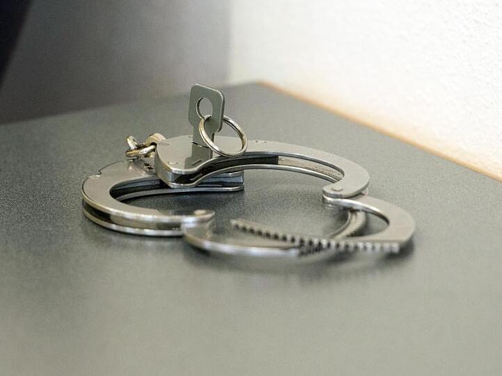 Handschellen liegen auf einem Tisch. Foto: Armin Weigel/dpa/Symbolbild
