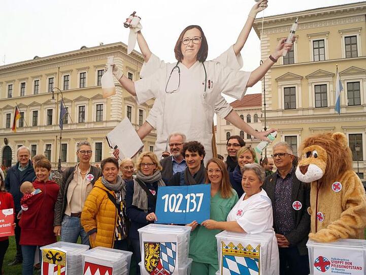 Natascha Kohnen (SPD), Ates Gürpinar (Linke), und Pflegekräfte halten ein Schild mit der Zahl 102 137. Foto: Stefan Jagel