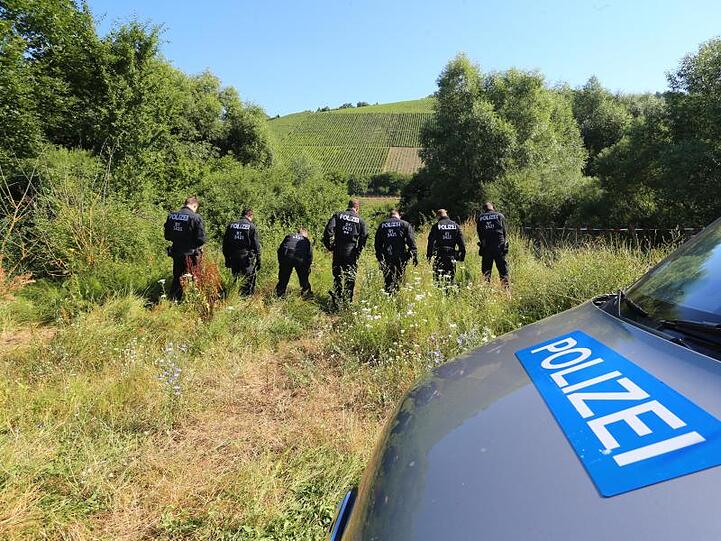 ILLUSTRATION - Polizisten durchsuchen neben einem Weg das Gelände nach Spuren. Foto: Karl-Josef Kildenbrand/Archiv