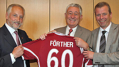 Club-Vize Siegfried Schneider (li.) überreicht Sportbürgermeister Horst Förther (M.) das Ehrentrikot. OB Ulrich Maly hilft beim Halten.