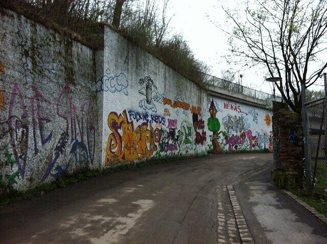 ... und hier, wenige Meter von dem Treff entfernt, zieht sich buntes Graffiti an der weißen Wand.