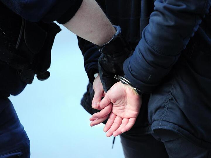 Ein Mann wird in Handschellen abgeführt. Foto: Daniel Reinhardt/dpa/Symbolbild