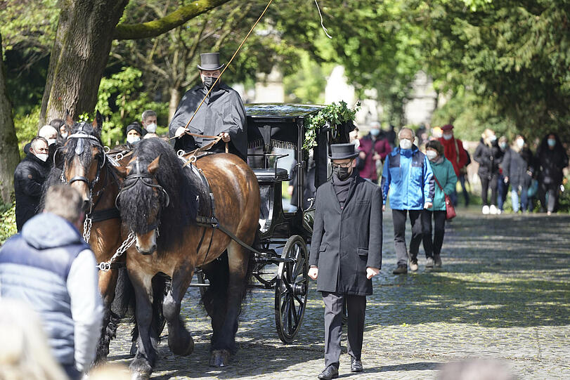 Zwei Pferde ziehen den schwarzen Sarg.