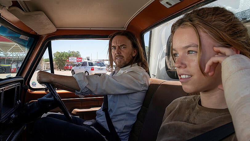 Lachlan "Lucky" Flynn (Tim Minchin) bildet mit der jungen Meg (Milly Alcock) eine Fahrgemeinschaft wider Willen. Lachlan "Lucky" Flynn (Tim Minchin) bildet mit der jungen Meg (Milly Alcock) eine Fahrgemeinschaft wider Willen.
