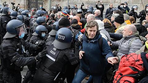 Einsatzkräfte der Polizei halten bei einer Kundgebung Teilnehmer zurück.