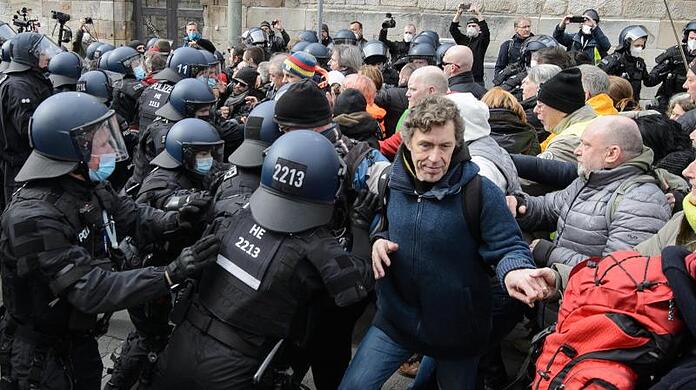 Einsatzkräfte der Polizei halten bei einer Kundgebung Teilnehmer zurück.