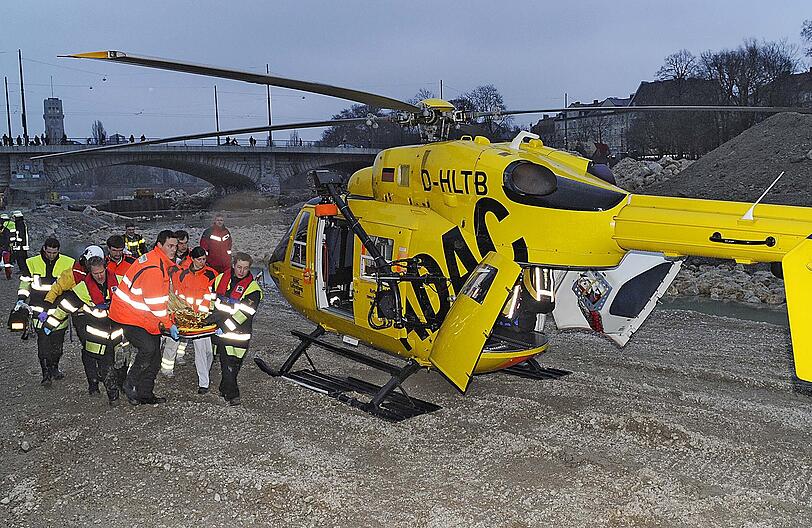 Helfer bringen die Frau auf einer Trage zum Rettungshubschrauber.