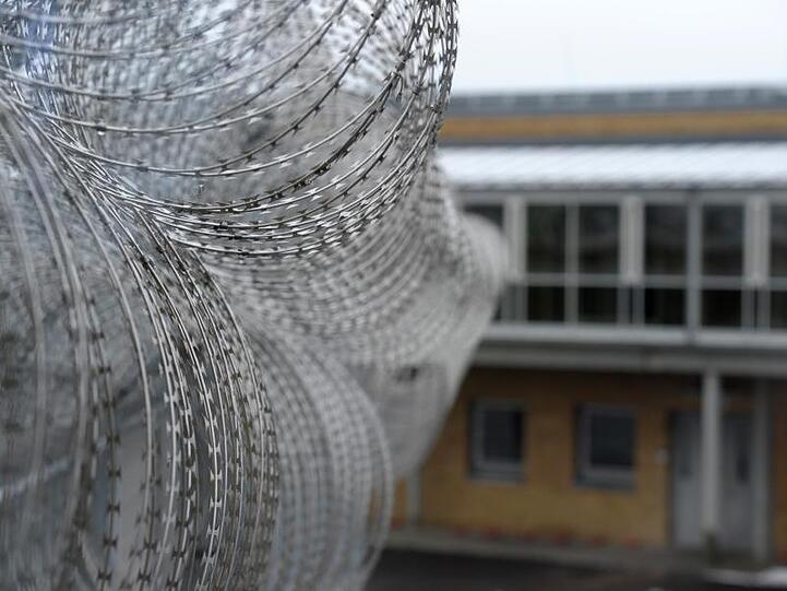 Stacheldraht sichert eine Mauer der Justizvollzugsanstalt in Würzburg. Foto: David Ebener/Archivbild
