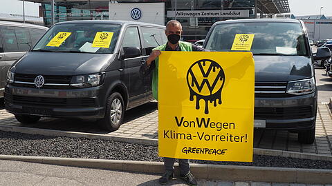 Ein Greenpeace-Aktiver mit einem Plakat vor dem Volkswagen Zentrum Landshut.