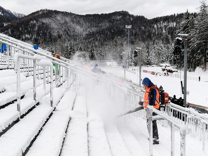 Helfer befreien die Zuschauertribünen in Ruhpolding vom Schnee.