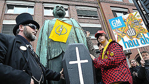 Was Adam Opel wohl zu dem Hick-Hack um den Traditionskonzern sagen würde? Rüsselsheimer Mitarbeiter protestieren mit einem Sarg vor der Statue des Firmengründers.