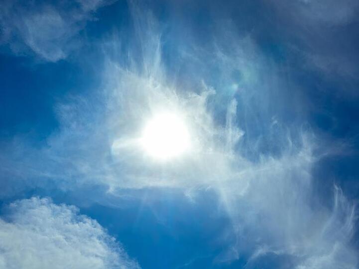 Die Sonne scheint am Himmel durch Wolken. Foto: Markus Scholz/dpa/Archivbild