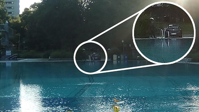 Das Auto am Beckenrand des Ungererbades. Links sieht man den Mitarbeiter, der mit einem Schlauch Wasser auf sein Gefährt spritzt.