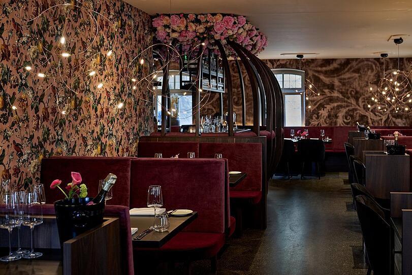 Bunte Tapete, elegante Sitzbereiche und eine klar abgetrennte Bar prägen den großen Raum im Erdgeschoss.