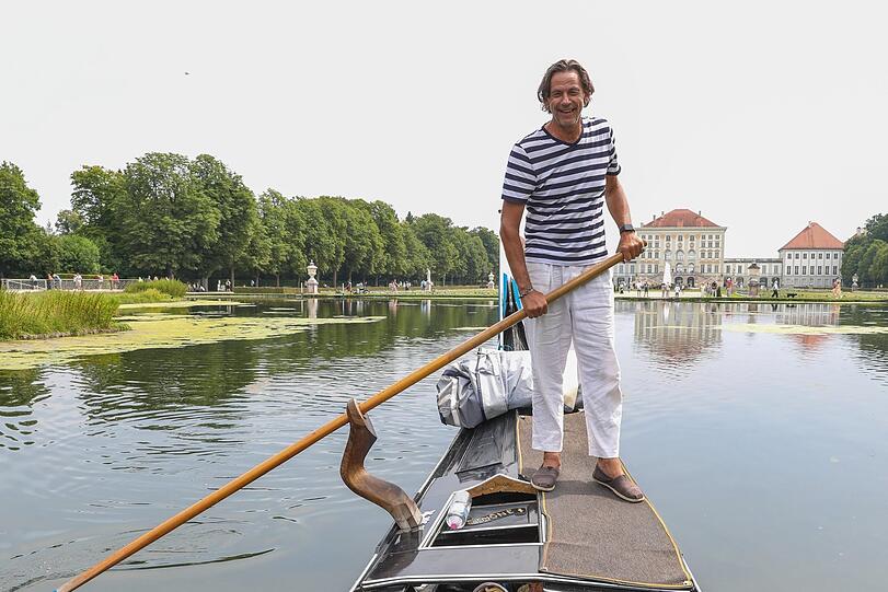 Maximilian Koch am Ruder seiner Gondel vor der Kulisse von Schloss Nymphenburg. Das schwarz glänzende Gefährt, das wirklich aus Venedig kommt, ist elf Meter lang.