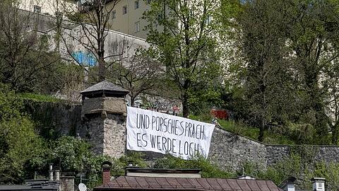 Ein Transparent mit der Aufschrift "Und Porsche sprach es werde Loch" hängt am Kapuzinerberg. In Salzburg demonstrierten Aktivisten gegen den geplanten Bau eines privaten Autotunnels von Wolfgang Porsche.