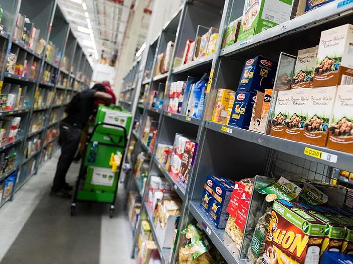 Ein Mitarbeiter des Lebensmittellieferdienstes Amazon Fresh packt bestellte Waren in eine Transporttasche (Archivbild).