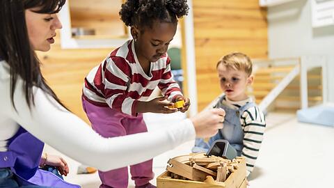 Kita-Kinder spielen mit einer Erzieherin.