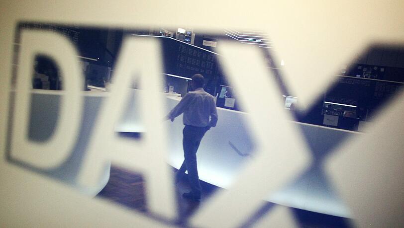 Ein Händler geht über das Parkett in der Börse in Frankfurt am Main und spiegelt sich dabei in einem Logo des Deutschen Aktienindexes (Dax). Foto: Fredrik von Erichsen Ein Händler geht über das Parkett in der Börse in Frankfurt am Main und spiegelt sich dabei in einem Logo des Deutschen Aktienindexes (Dax). Foto: Fredrik von Erichsen