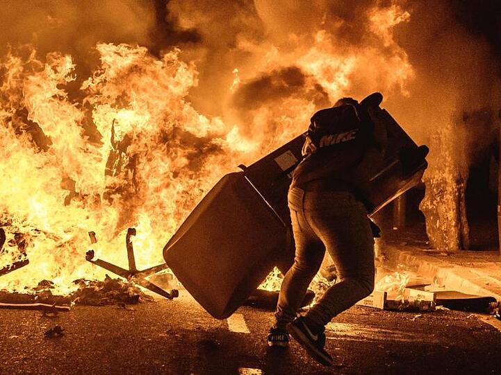 Ein Demonstrant wirft einen Mülleimer auf eine brennende Barrikade bei Protesten gegen die Verurteilung katalanischer Separatistenführer.
