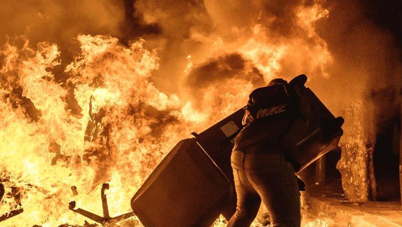 Ein Demonstrant wirft einen Mülleimer auf eine brennende Barrikade bei Protesten gegen die Verurteilung katalanischer Separatistenführer. Ein Demonstrant wirft einen Mülleimer auf eine brennende Barrikade bei Protesten gegen die Verurteilung katalanischer Separatistenführer.
