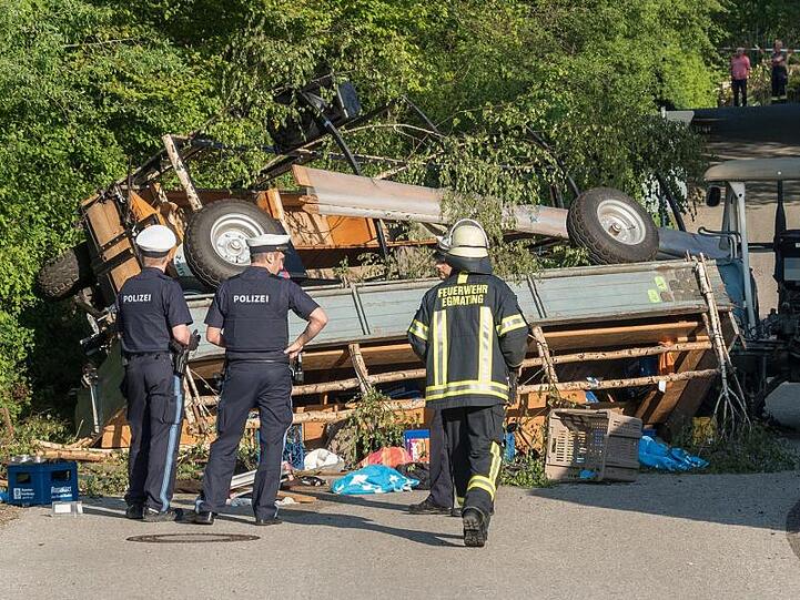 Polizisten und ein Feuerwehrmann vor zwei umgestürzten Traktoranhängern. Foto: Stefan Roßmann