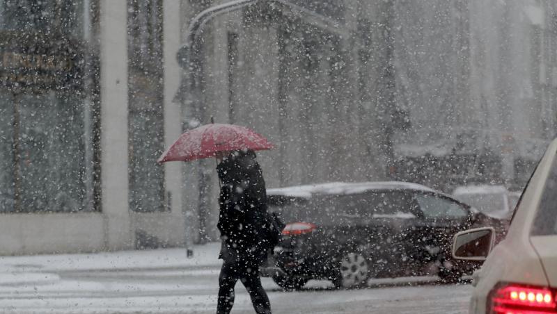 Ein Frau mit Schirm geht im Schneetreiben über eine Straße in Köln. Ein Frau mit Schirm geht im Schneetreiben über eine Straße in Köln.