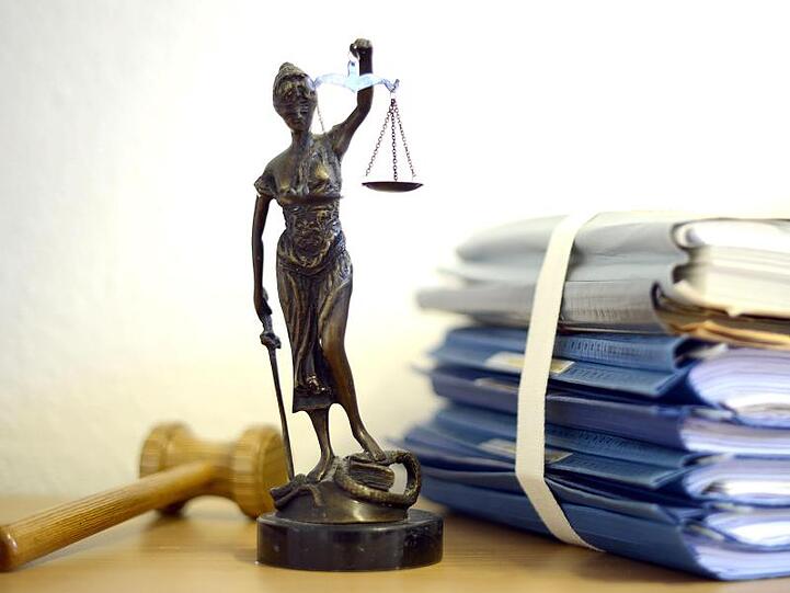 Justitia mit Holzhammer und Aktenstapel. Foto: Volker Hartmann/dpa/Symbolbild