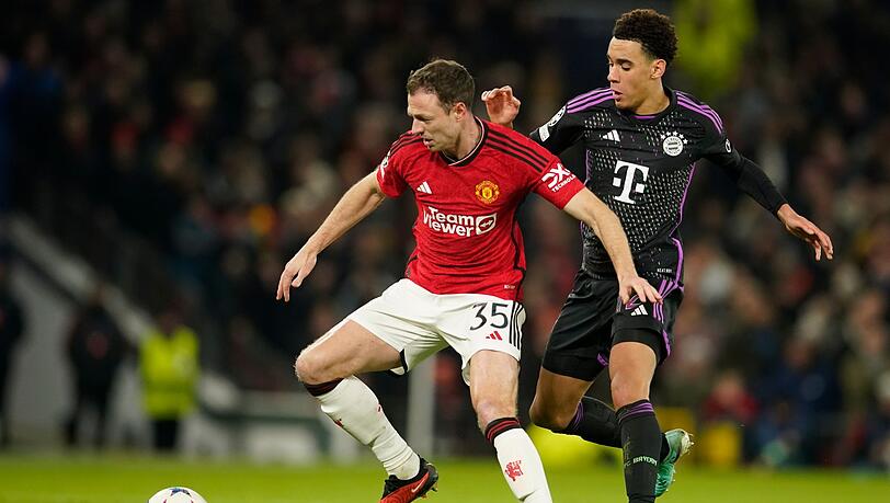 Manchester Uniteds Jonny Evans (l) wird von Münchens Jamal Musiala angegriffen.