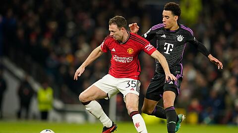 Manchester Uniteds Jonny Evans (l) wird von Münchens Jamal Musiala angegriffen.