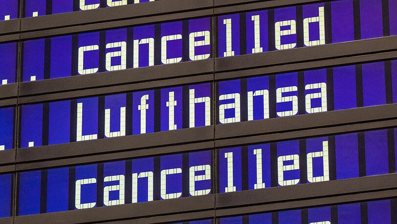 Anzeigentafeln zeigen "cancelled" und "Lufthansa" am Flughafen München an.