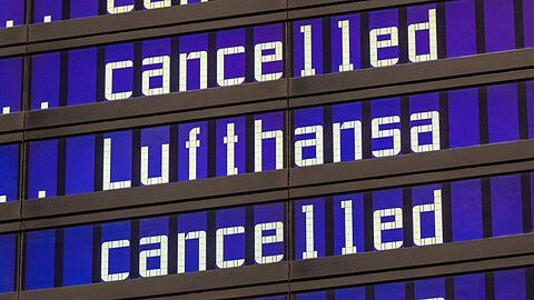 Anzeigentafeln zeigen "cancelled" und "Lufthansa" am Flughafen München an.