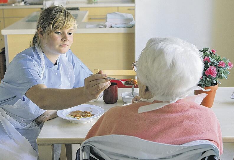 Eine Pflegerin hilft einer demenzkranken Frau