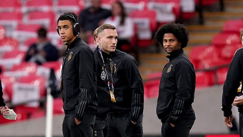 Die deutschen Nationalspieler Jamal Musiala (l-r), David Raum und Serge Gnabry schauen sich vor dem Spiel im Stadion um.