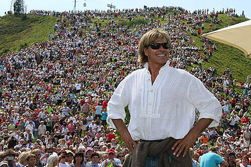 Als Hansi eintrifft singen 10.000 Fans seine Hymne. Hansi ist stolz auf seine Fans weil sie "diszipliniert" sind, wie er sagt.